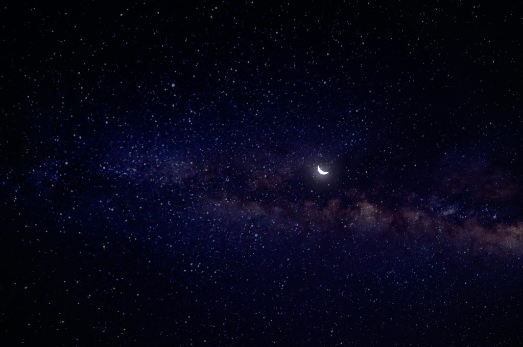 A serene view of a crescent moon nestled in a star-filled night sky with the Milky Way.