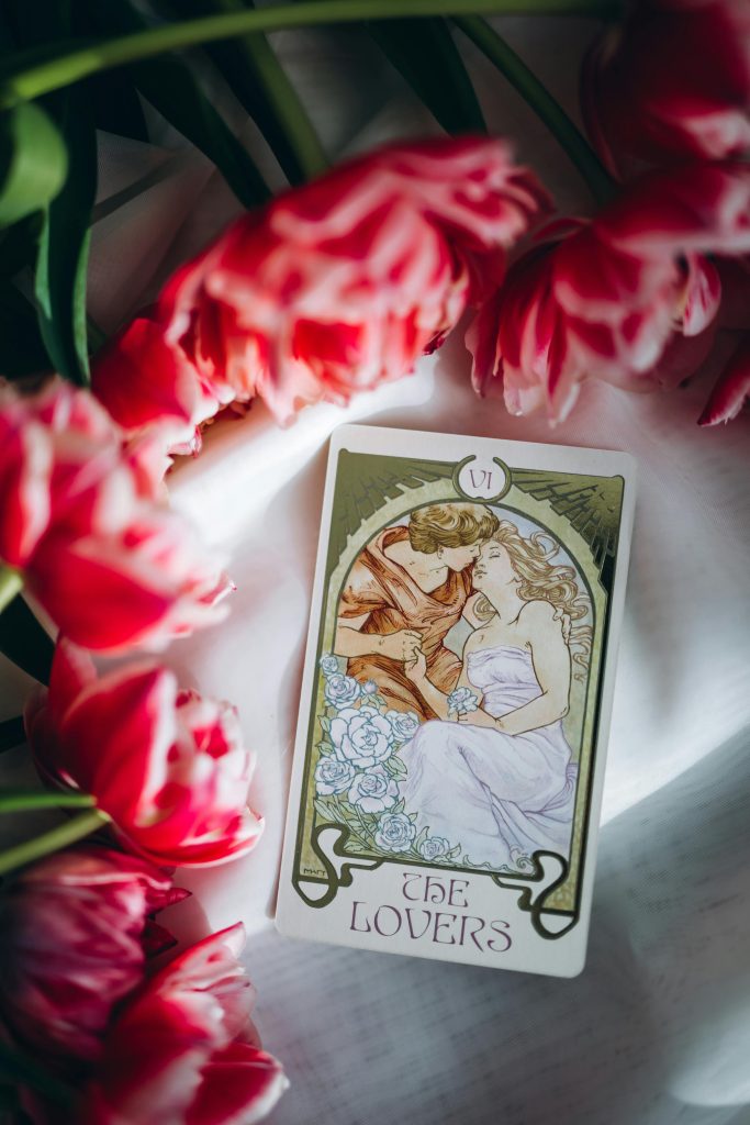 The Lovers tarot card among vibrant pink tulips symbolizing love and harmony.